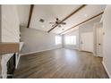 Spacious living room with modern wood laminate flooring, ceiling fan, exposed ceiling beams, and a fireplace at 20802 N 7Th Pl, Phoenix, AZ 85024