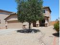 Two-story home featuring a two-car garage, desert landscaping, and a tree in the front yard at 2434 E San Manuel Rd, San Tan Valley, AZ 85143