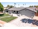 Beautiful single story home boasting a brick driveway, green lawn, and two car garage at 5919 S Newberry Rd, Tempe, AZ 85283
