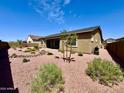 Serene backyard featuring desert landscaping, mature shrubs, and a covered patio at 20171 W Cheery Lynn Rd, Buckeye, AZ 85396