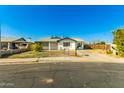 Quaint single-story house featuring a xeriscaped front yard and a sunny blue sky background at 214 W June Cir, Mesa, AZ 85201