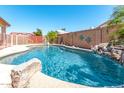 An inviting backyard pool with rock features and decor surrounded by a block fence and trees at 3016 N 109Th Ave, Avondale, AZ 85392
