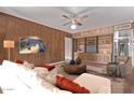 Comfortable living room features wood-paneled walls, ceiling fan, a white couch and a large built-in bookcase at 3823 W Berridge Ln, Phoenix, AZ 85019