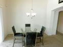 Cozy dining room with a modern glass table, upholstered chairs, and a chandelier at 44147 W Snow Dr, Maricopa, AZ 85138