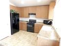 Functional kitchen featuring wooden cabinets and black appliances with laminate countertops at 44147 W Snow Dr, Maricopa, AZ 85138