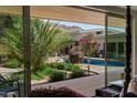 Relaxing backyard pool area with lush landscaping and inviting seating, visible through sliding glass doors at 6417 N 52Nd Pl, Paradise Valley, AZ 85253