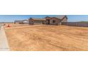 Exterior of tan single-story house and adjacent lot in desert setting with blue sky at 9485 W Sandstone Mountain Dr, Casa Grande, AZ 85194
