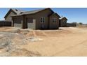 Spacious three-car garage with paneled doors on a home that needs landscaping at 9485 W Sandstone Mountain Dr, Casa Grande, AZ 85194