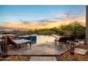 Outdoor pool area with lounge chairs, stone pavers, and warm lighting at 11986 N 134Th Pl, Scottsdale, AZ 85259