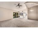 Open living room featuring carpet floors, vaulted ceilings, and sliding glass doors to the backyard at 1407 W Utopia Rd, Phoenix, AZ 85027