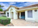 Inviting front porch with tile flooring, blue bench, and decorative sun accent under a partly cloudy sky at 14605 S 35 Pl, Phoenix, AZ 85044
