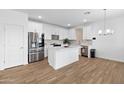 Kitchen featuring white cabinets, center island, stainless steel appliances and wood-look floors at 16956 W Alice Ave, Waddell, AZ 85355