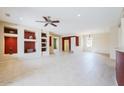 Spacious living room featuring tile floors, a ceiling fan, and built in display shelving at 17192 W Hermosa Dr, Surprise, AZ 85387