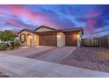 Attractive desert home with a 3-car garage, paver driveway, and well-manicured landscaping at sunset at 19873 W San Juan Ave, Litchfield Park, AZ 85340