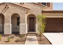Inviting front entrance featuring an arched entryway, a well-maintained walkway, and a manicured garden at 20473 W Legend Trl, Buckeye, AZ 85396