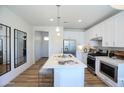Modern kitchen boasts stainless steel appliances, white cabinets, an island with seating, and hardwood flooring at 2205 N Peden Dr, Chandler, AZ 85225