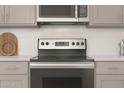 Close up of a modern electric range, gray cabinets and subway tile backsplash at 23443 W Albeniz Pl, Buckeye, AZ 85326