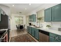 Charming kitchen with teal cabinetry, stainless steel appliances, and a cozy dining area, perfect for everyday living at 7722 W Pipestone Pl, Phoenix, AZ 85035