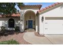 Inviting front entrance featuring a bright blue door, an arched entryway, and well-maintained landscaping at 8943 N 80Th Pl, Scottsdale, AZ 85258