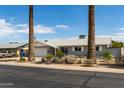 Lovely single-story house with a two-car garage, complemented by mature palm trees and desert flora at 100 E Geneva Dr, Tempe, AZ 85282