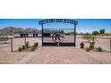 Dramatic entrance to Rancho Los Ramos with a wrought iron gate, decorative stone accents and paver entry at 10910 N Thunderbird Rd, Maricopa, AZ 85139