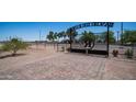 Beautiful view through wrought-iron entrance gate to property with paver entry, plants, and desert landscape at 10910 N Thunderbird Rd, Maricopa, AZ 85139
