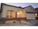 A charming home exterior with an arched entrance, well-maintained landscaping, and a two car garage at 1255 N Arizona Ave # 1216, Chandler, AZ 85225
