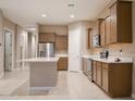Open-concept kitchen featuring wooden cabinets, stainless steel appliances, an island, and tile flooring at 1255 N Arizona Ave # 1216, Chandler, AZ 85225