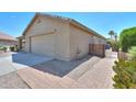 View of the side of the house with a 2-car garage and a brick walkway to an iron gate at 135 S Verde Ln, Casa Grande, AZ 85194