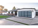 A modern house with black window frames, a glass garage door, and minimalist landscaping at 1539 W Puget Ave, Phoenix, AZ 85021