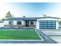 A charming home with a green lawn, brick accents, and a modern black-framed glass garage door at 1539 W Puget Ave, Phoenix, AZ 85021
