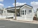 Cozy manufactured home with covered parking and a front porch, plus low maintenance landscaping at 272 S Cinnabar Dr, Apache Junction, AZ 85119