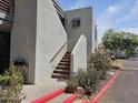 Condo exterior featuring a staircase with concrete steps, gray siding, and lush landscaping in front at 3420 W Danbury Dr # C218, Phoenix, AZ 85053
