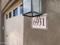 Close up of address number 6931, next to garage door and exterior light fixture on tan wall at 6931 E Teton Cir, Mesa, AZ 85207