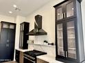 Kitchen with stainless steel appliances, white countertops, a black exhaust hood, and black framed glass cabinets at 6931 E Teton Cir, Mesa, AZ 85207