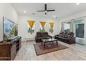 Spacious living room features wood-look tile flooring, a ceiling fan, and ample natural light from large windows at 16027 N 74Th Ln, Peoria, AZ 85382