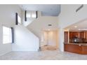 Bright living room with soaring ceilings, tile floors, and open access to a kitchen with stained cabinets at 231 N Nash Way, Chandler, AZ 85225