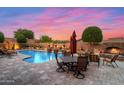 Beautiful backyard with a pool, fireplace, and outdoor seating area under a colorful sunset sky at 42037 N Bradon Way, Phoenix, AZ 85086