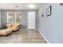 Bright living room featuring neutral walls, wood-look tile flooring, a front door, and a comfortable leather armchair at 46185 W Dutchman Dr, Maricopa, AZ 85139
