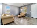 Bright living room with wood-look tile flooring, neutral walls, comfortable furniture and lots of natural light at 46185 W Dutchman Dr, Maricopa, AZ 85139