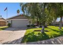 Well-kept single-story home with a green lawn, mature tree, and a two-car garage at 4711 S Los Feliz Dr, Tempe, AZ 85282