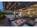 Inviting back patio featuring a fire pit, seating under a pergola with string lights, and an outdoor kitchen at 10154 E Bergeron Ave, Mesa, AZ 85212
