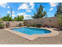 Private backyard pool surrounded by mature landscaping and a decorative wall, creating an ideal outdoor retreat at 125 N 107Th Dr, Avondale, AZ 85323