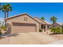 Charming single story home with desert landscaping, lush palms, and a two-car garage at 16280 W Desert Winds Dr, Surprise, AZ 85374