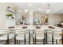 Open kitchen with island seating, pendant lighting, quartz countertops, and stainless steel appliances at 23417 W Burton Ave, Buckeye, AZ 85326