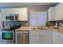 Well-lit kitchen with stainless steel appliances, stylish backsplash, and a double basin stainless steel sink at 287 W Liberty Ln, Gilbert, AZ 85233