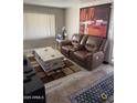 Comfortable living room with leather reclining sofa, decorative rug, light-colored wood flooring, and modern art at 4065 E University Dr # 242, Mesa, AZ 85205