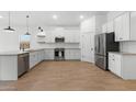 Modern kitchen featuring stainless steel appliances, white cabinets, and wood-look tile floors at 42460 W Peters Dr, Maricopa, AZ 85138