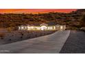 Desert home exterior featuring desert landscaping and a long driveway at dusk at 9357 W Canyon Verde Dr, Casa Grande, AZ 85194