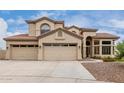 Inviting two-story home featuring a three-car garage, desert landscaping, and a tile roof at 9825 E Gary St, Mesa, AZ 85207